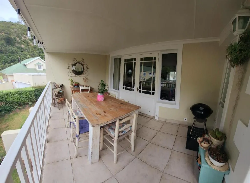 Covered patio with wooden dining table and braai grill, garden views