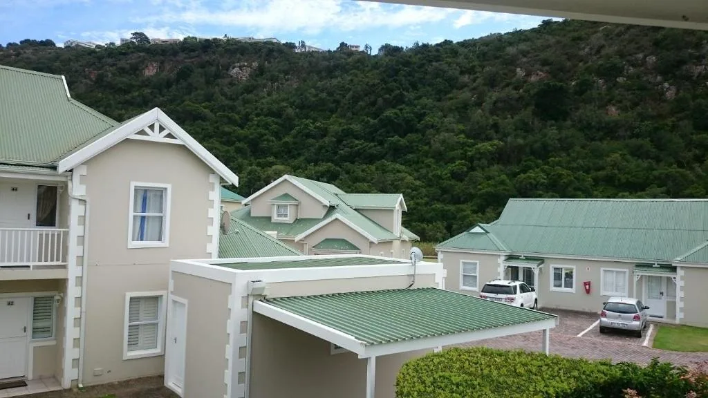 Cream and white villa units with green metal roofs nestled against lush hillside