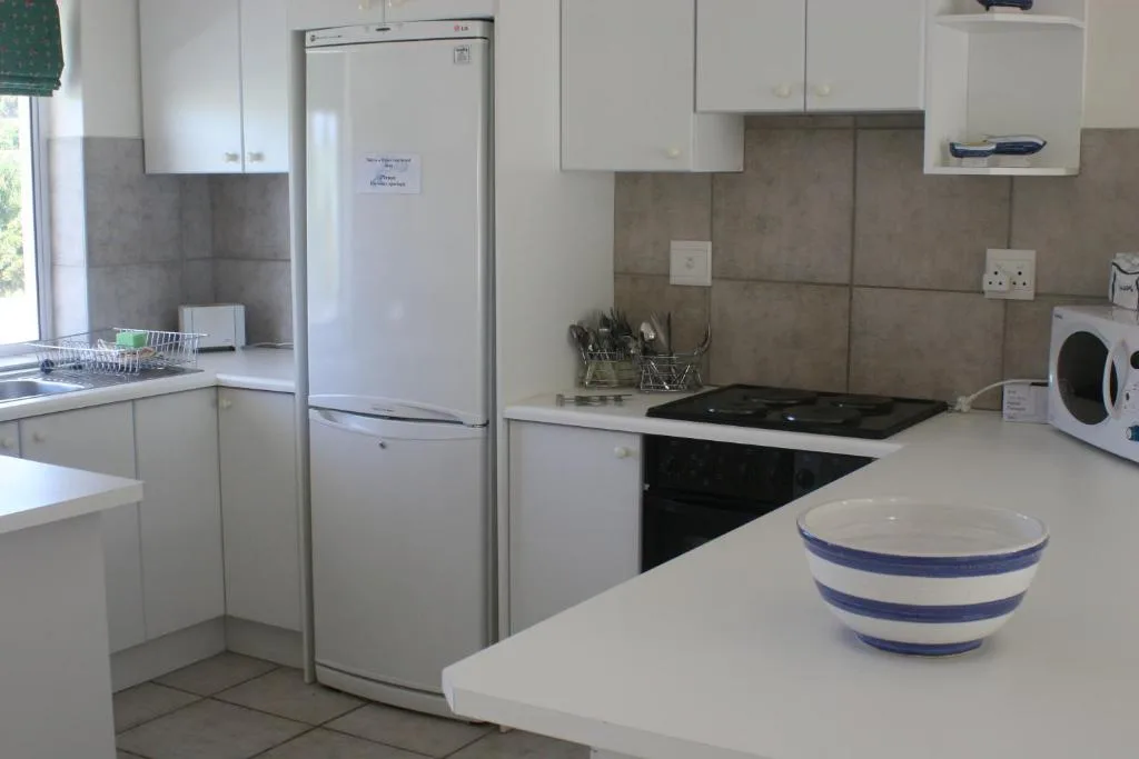 Modern kitchen with white cabinetry, stainless fridge, and black cooktop