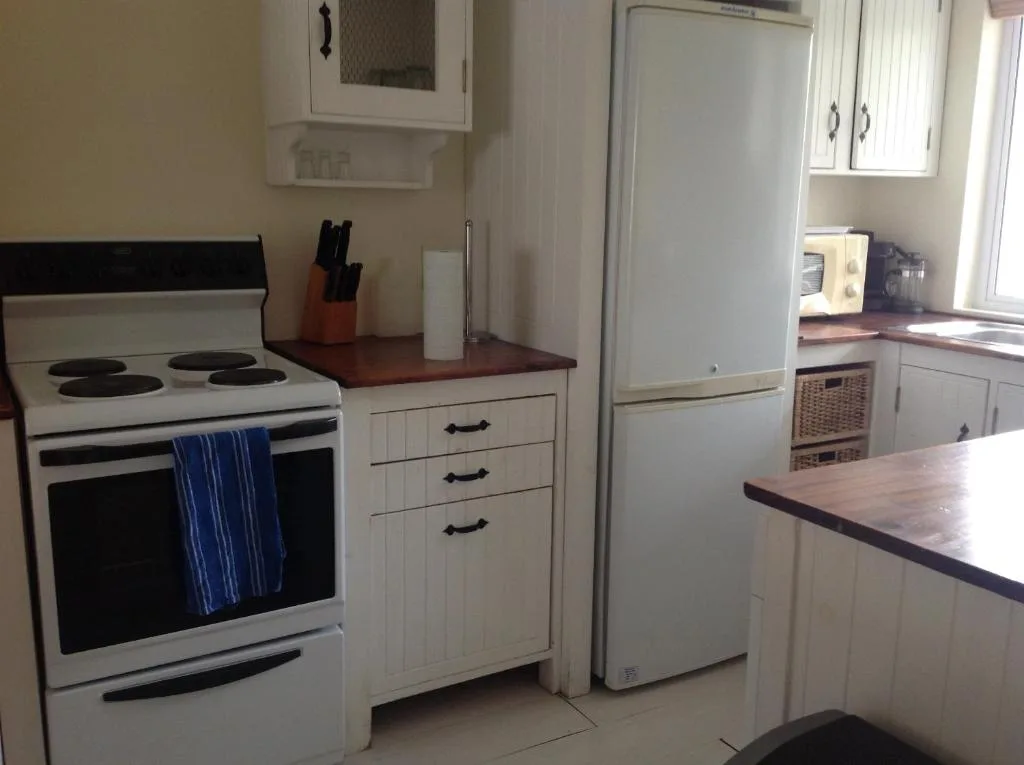 Compact kitchen with white appliances, wooden countertops, and storage cabinets