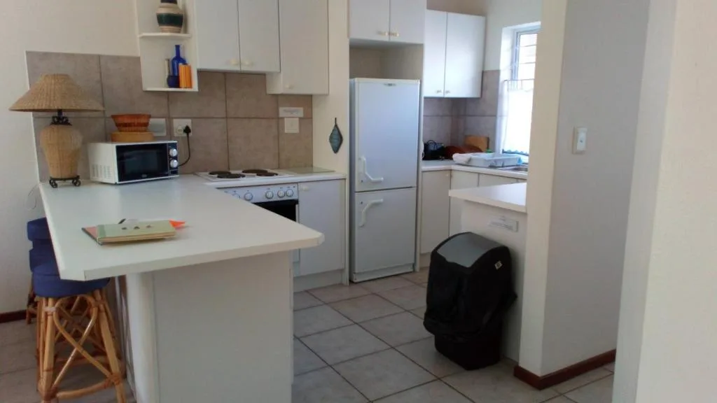 Compact kitchen with white cabinetry, island counter, and stainless steel appliances