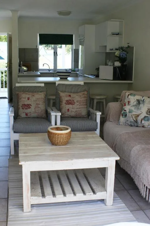 Open-plan living area with striped armchairs, coffee table, and kitchen view