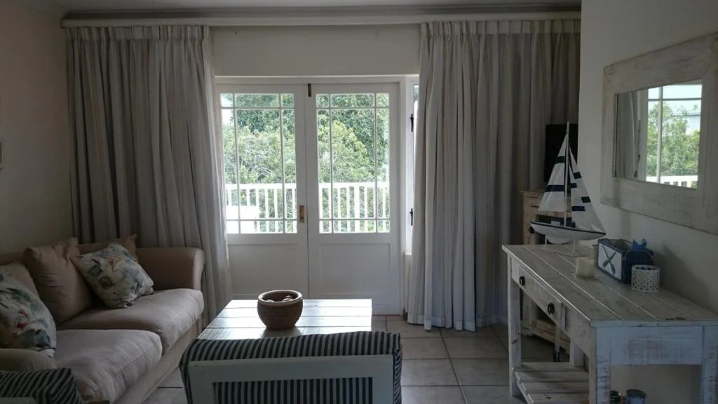 Bright lounge with cream sofa, striped ottoman, and glass doors to balcony