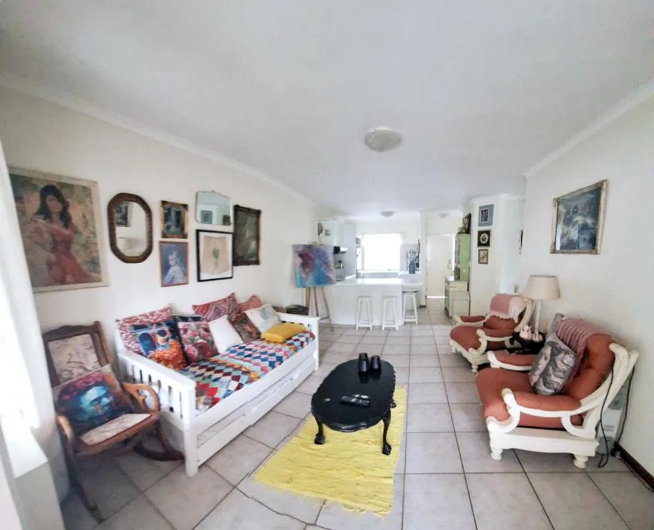 Open-plan living area with colorful artwork, seating, and bedroom visible