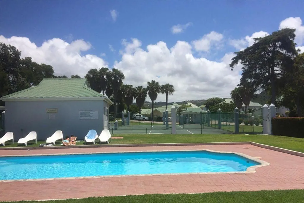 Rectangular swimming pool with lounge chairs and green changing facilities nearby