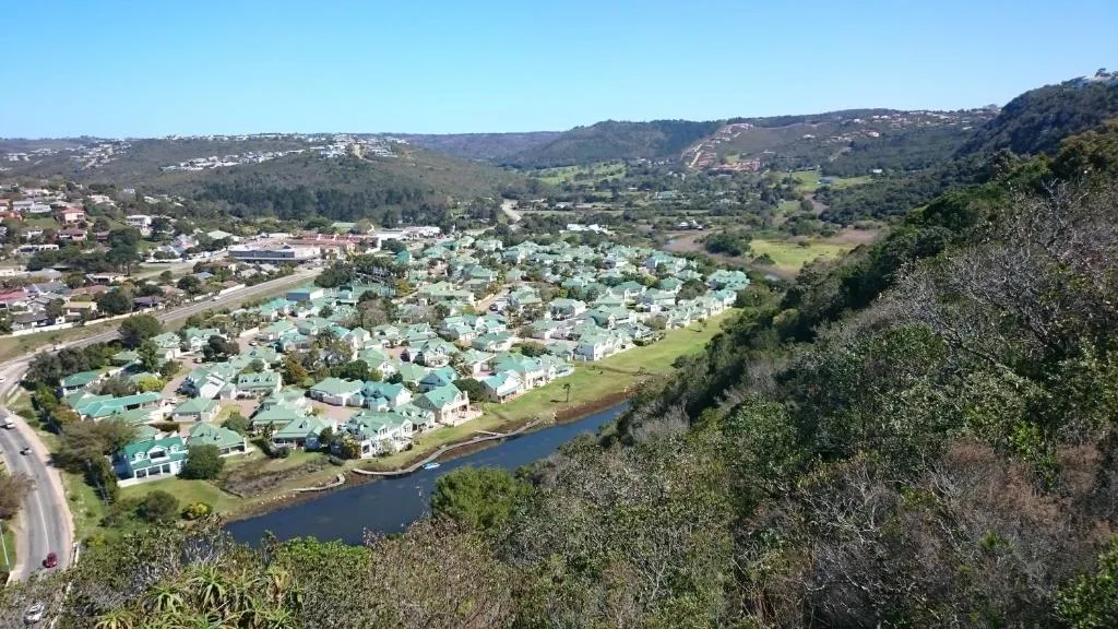 Aerial view of Plettenberg Bay suburb with river, homes, and forested hills