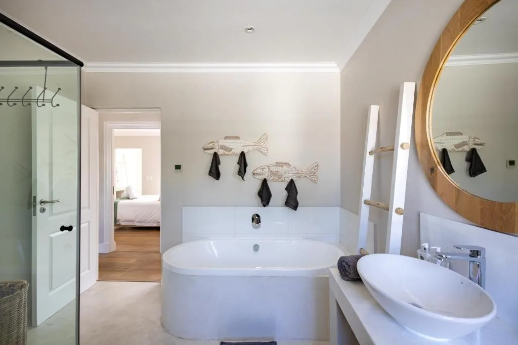 Modern bathroom with freestanding tub, double vanity, and wooden mirror