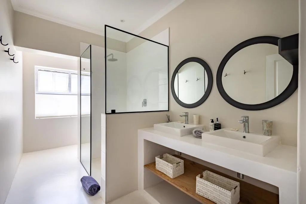 Modern bathroom with double vanity, black-framed mirrors, and walk-in shower