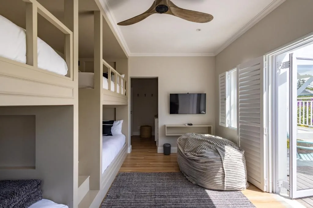 Bright bedroom with built-in bunk beds and woven chair near glass doors