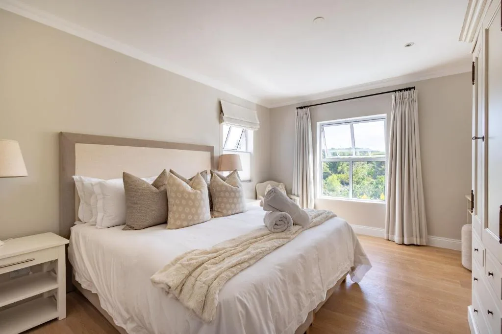 Spacious bedroom with bed, neutral decor, garden views through large windows