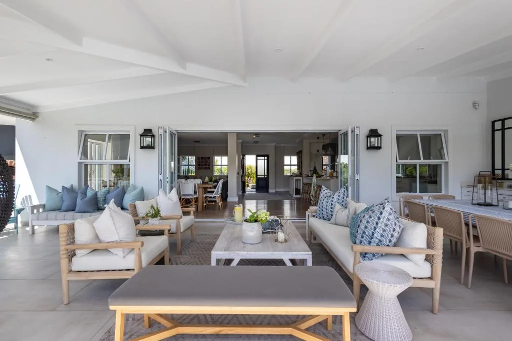 Spacious covered patio with wooden seating, blue cushions, and ocean views