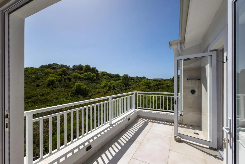 Spacious balcony with white railings overlooking lush green forest hills