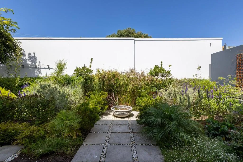 Landscaped garden pathway with fire pit and modern white villa