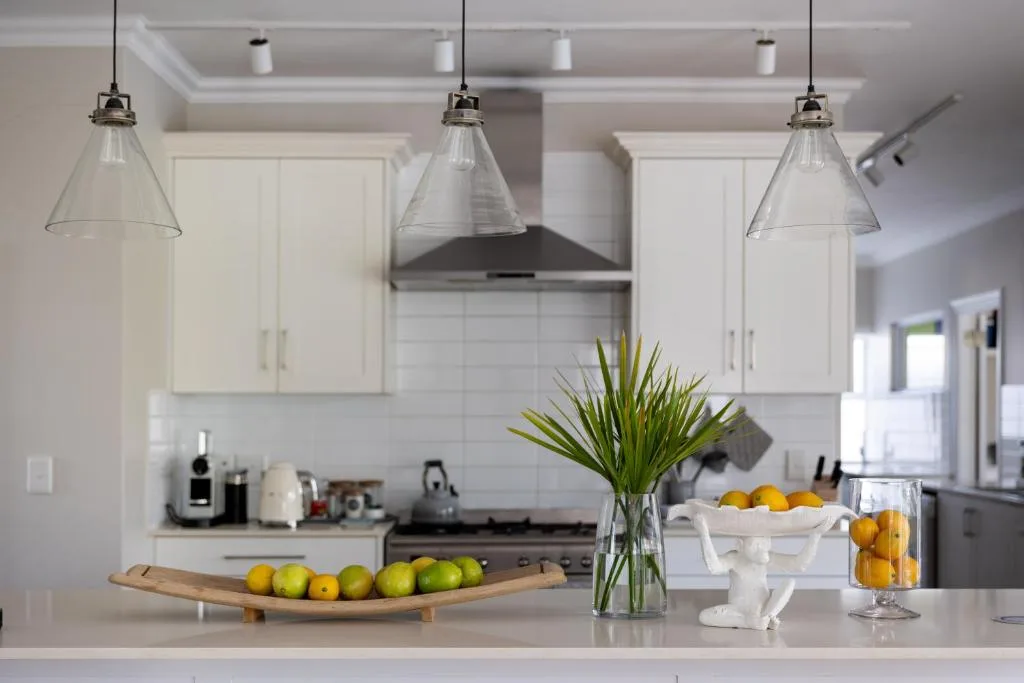 Modern white kitchen with pendant lights, island counter, fresh fruit display