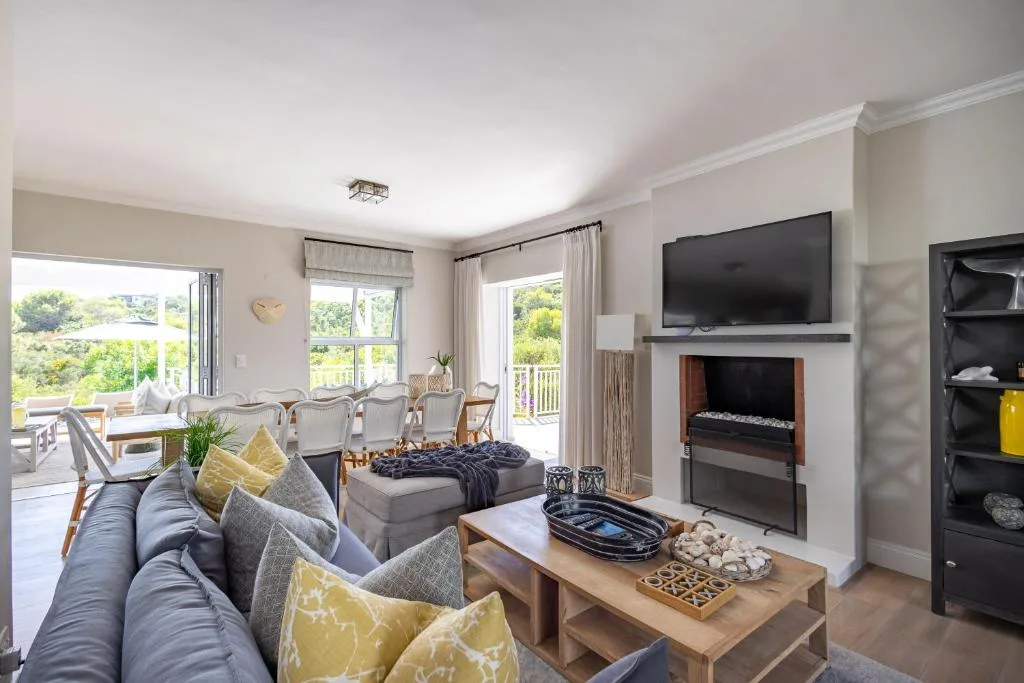 Spacious lounge with fireplace, TV, comfortable seating, and garden views