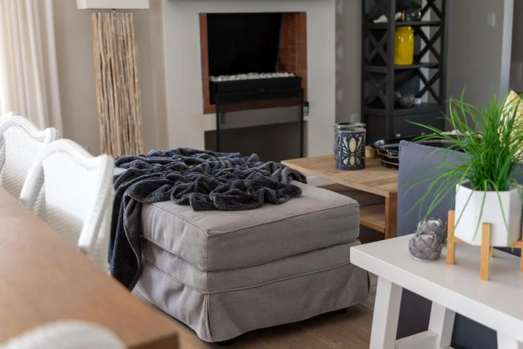 Modern lounge with upholstered ottoman, electric piano, and decorative plants