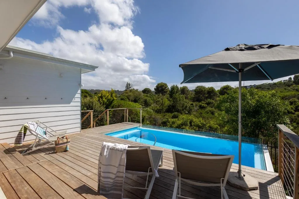 Swimming pool on wooden deck with umbrella and garden views