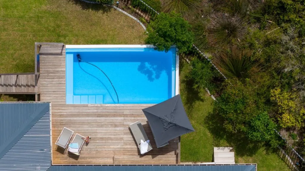 Aerial view of rectangular swimming pool with wooden deck and umbrella