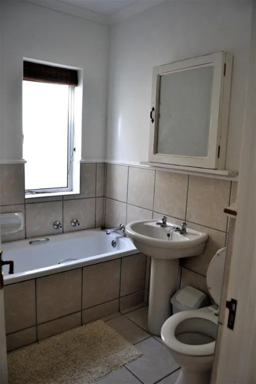 Bathroom with bathtub, pedestal sink, toilet, and window