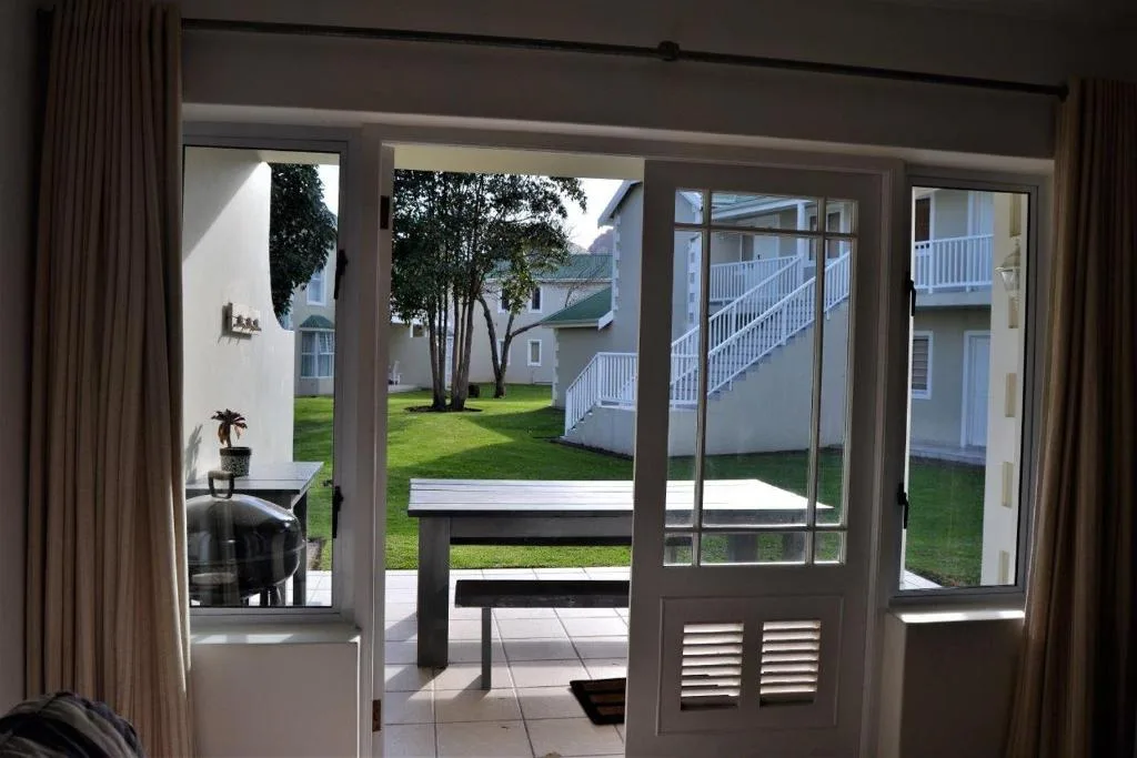 Glass sliding doors opening onto patio with white bench and manicured lawn