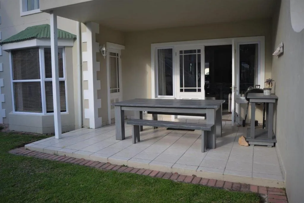 Covered patio with wooden dining table and benches, garden view