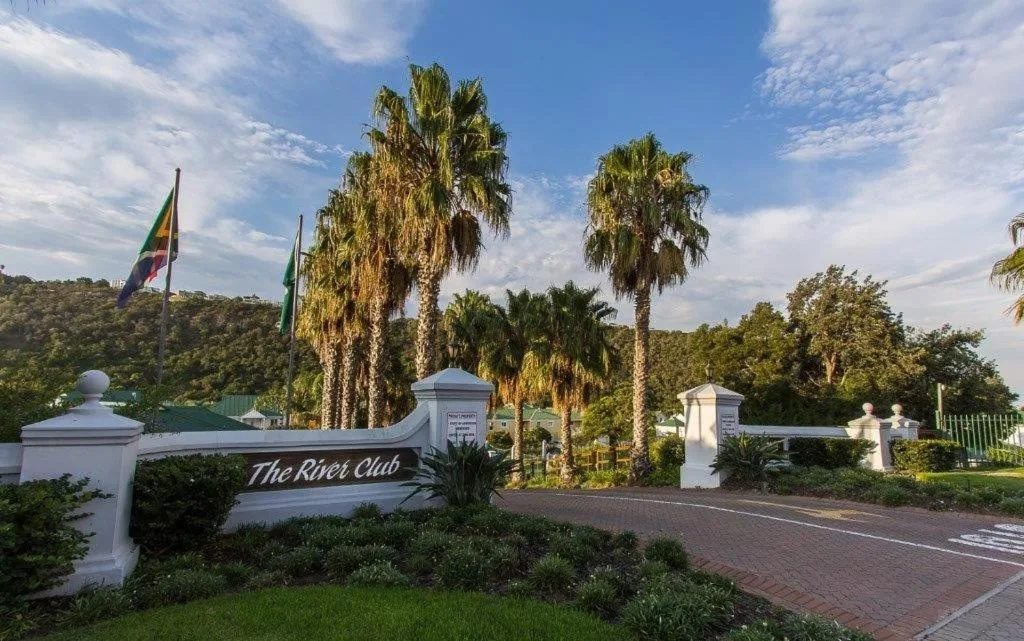 Gated entrance to The River Club with palm trees and manicured gardens