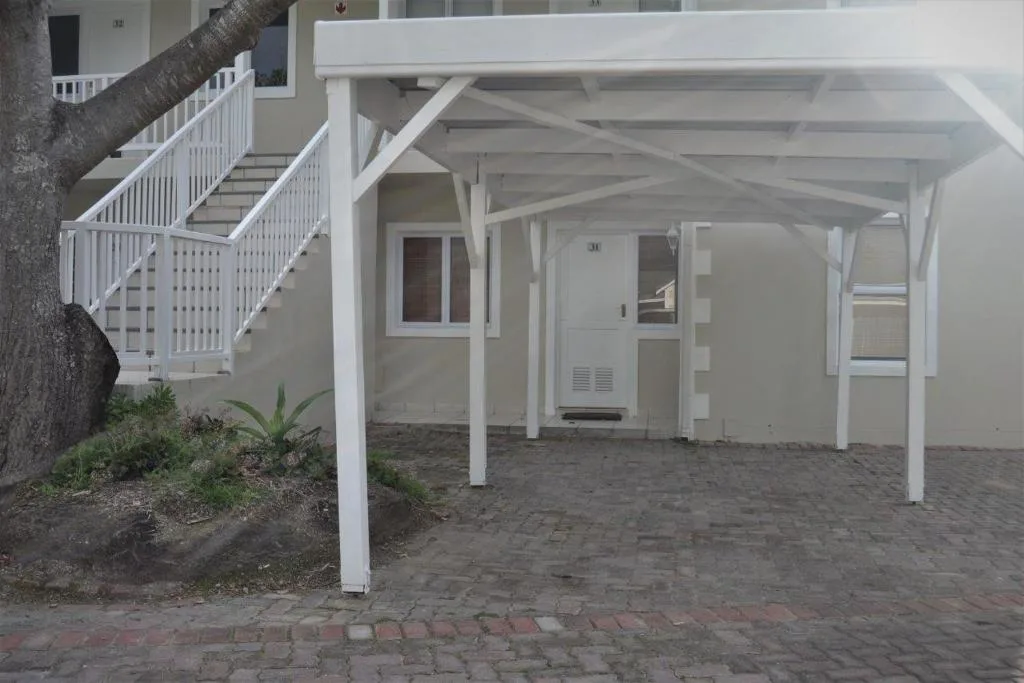 White-painted villa exterior with covered patio and brick paving