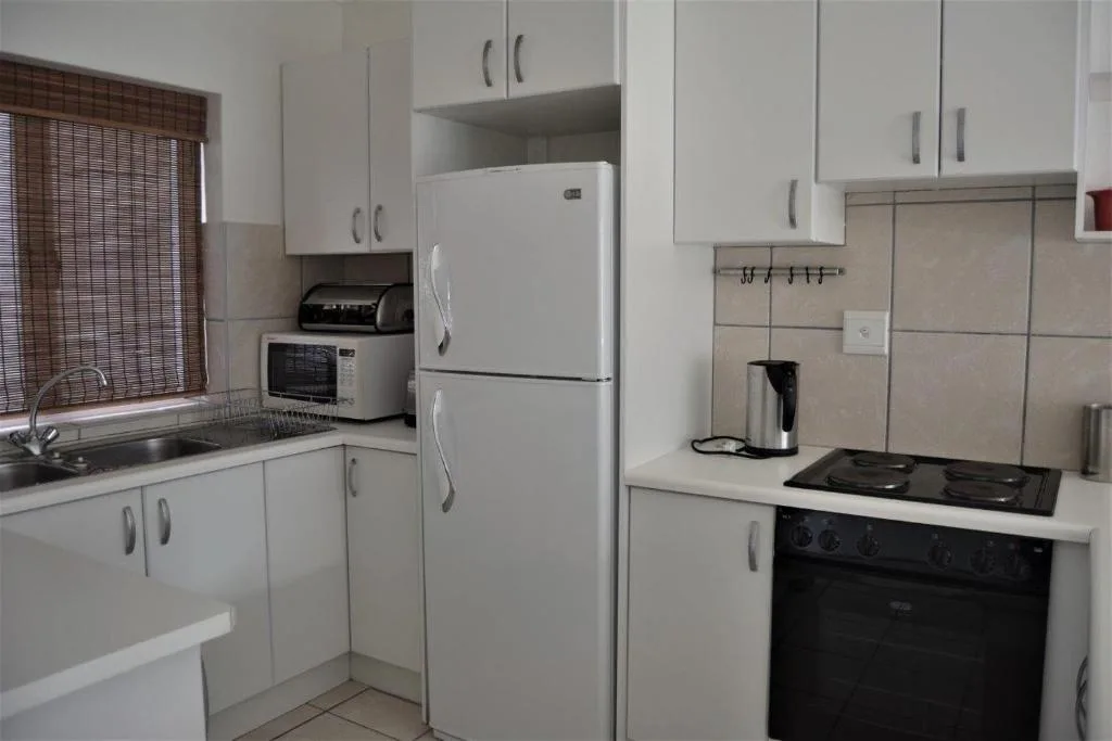 Compact kitchen with white cabinetry, stainless steel refrigerator, and black stove