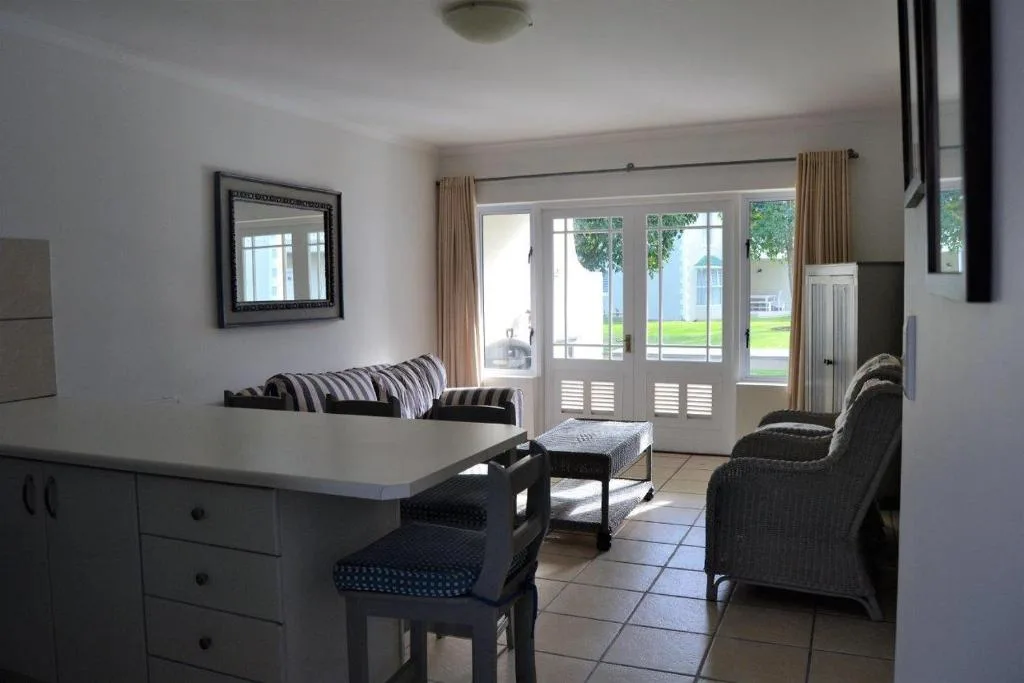 Open-plan lounge with striped sofa, armchairs, and glass doors overlooking garden