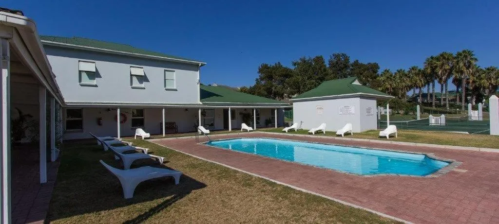 Blue swimming pool with loungers and white umbrellas near villa