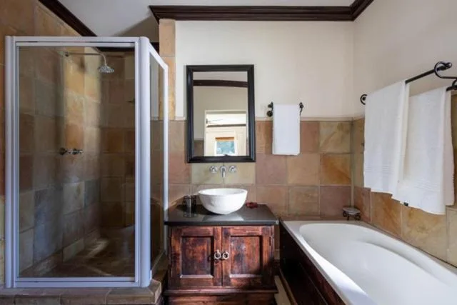 Bathroom with shower enclosure, vanity sink, and bathtub with warm tile accents