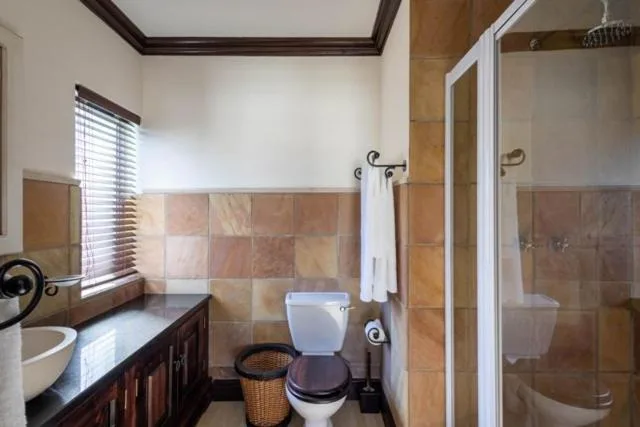 Bathroom with terracotta tiles, vanity sink, toilet, and shower enclosure