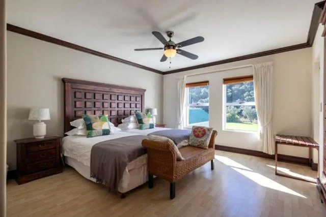 Bright bedroom with queen bed, ocean views through windows, ceiling fan