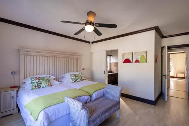 Bright bedroom with two twin beds, ceiling fan, and garden artwork