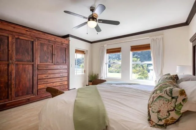 Spacious bedroom with wooden wardrobe and garden views through windows