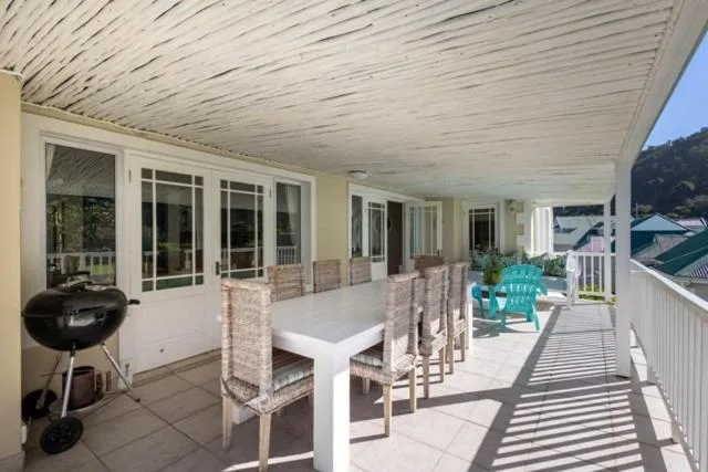 Covered patio with dining table, chairs, and braai grill overlooking garden