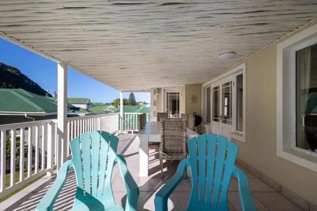 Covered deck with turquoise Adirondack chairs overlooking scenic garden views