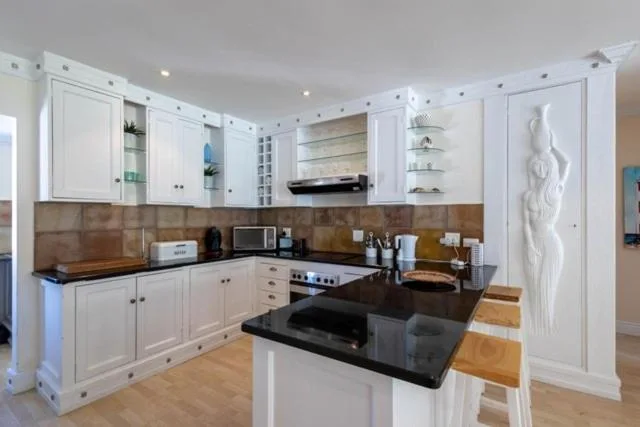 Modern kitchen with white cabinetry, black countertop island, and stainless steel appliances