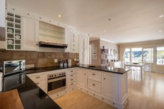 Modern kitchen with white cabinetry, black countertops, and stainless steel appliances