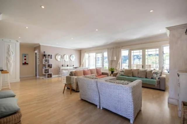 Spacious open-plan lounge with comfortable seating and large windows overlooking garden