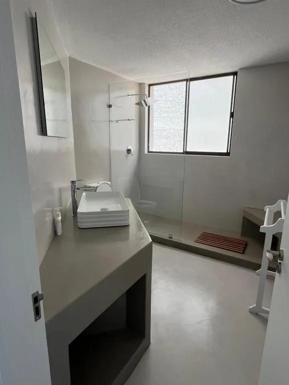 Modern bathroom with vanity sink, glass shower enclosure, and window