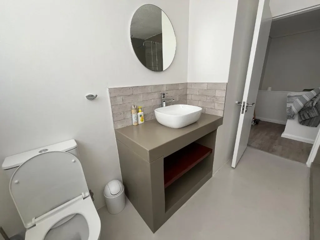 Modern bathroom with vessel sink, round mirror, toilet and subway tile backsplash
