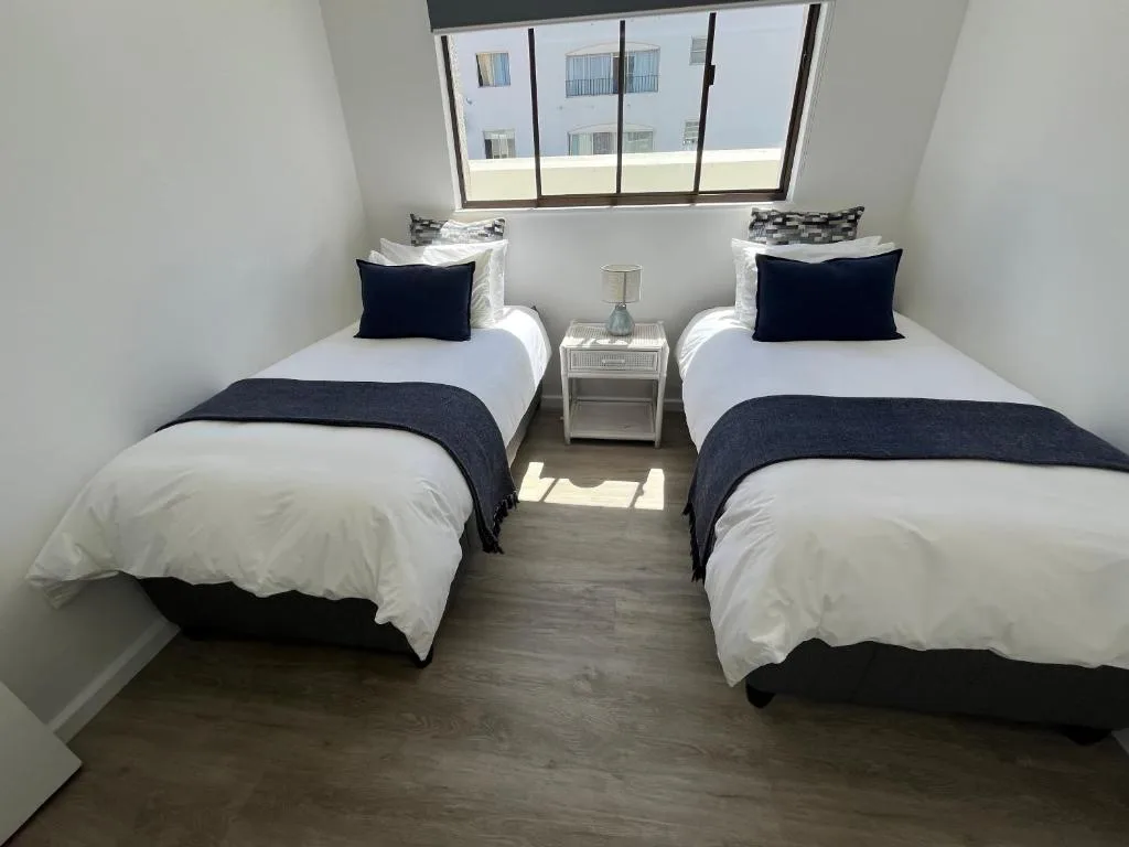 Twin bedroom with white linens, dark navy accents, and large window