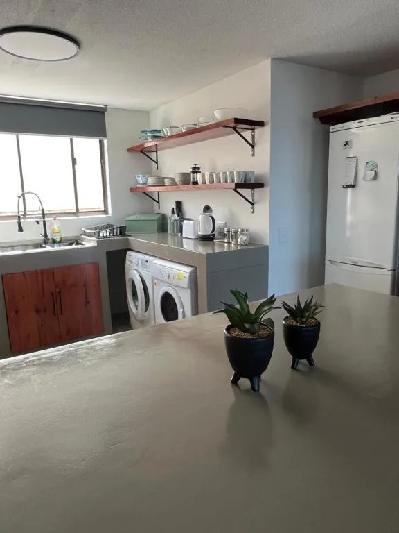 Modern kitchen with red cabinetry, wooden shelves, washing machine, and white refrigerator