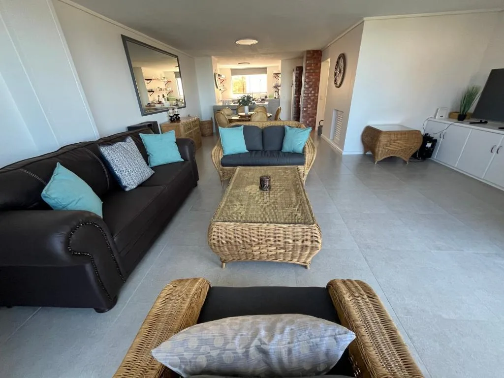 Spacious living room with black sofa, wicker furniture, and turquoise accents