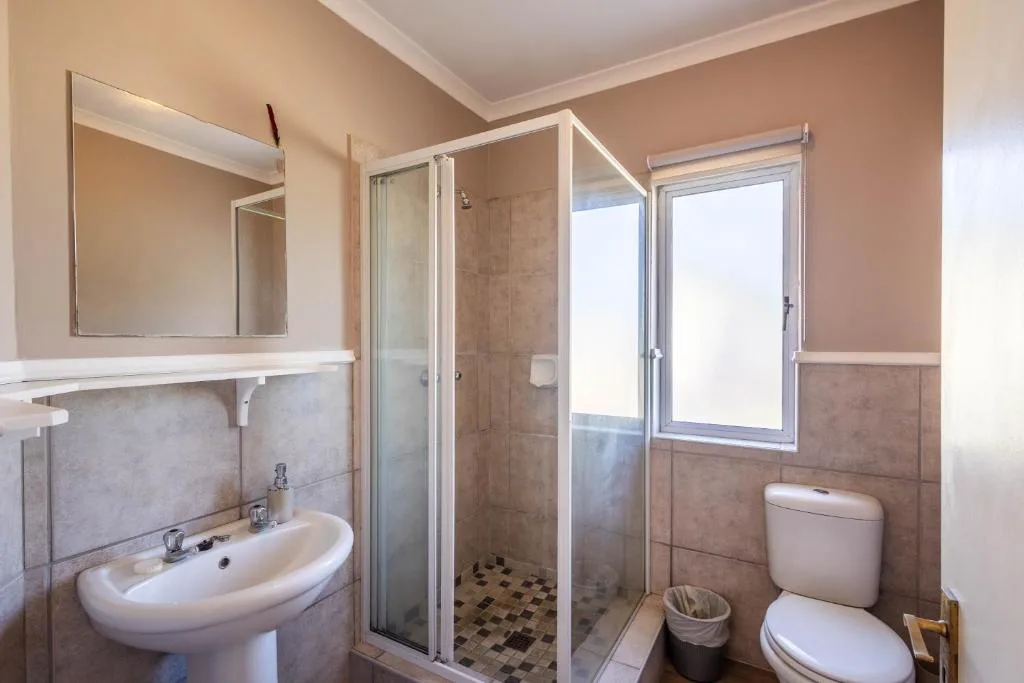 Modern bathroom with shower enclosure, vanity sink, and toilet