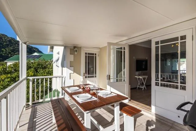 Covered outdoor deck with dining table overlooking lush garden views