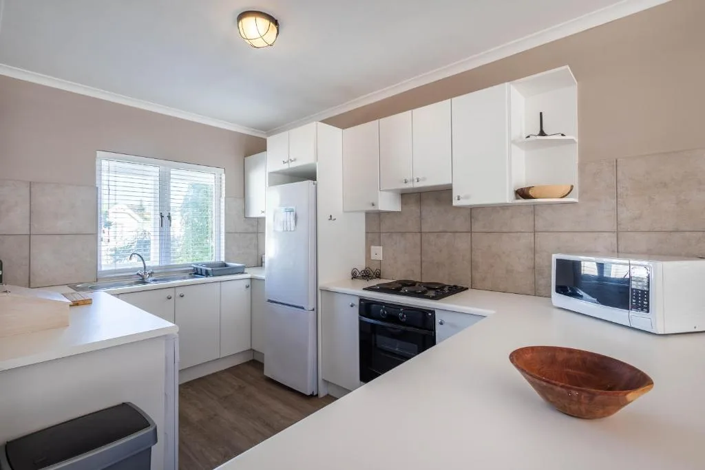 Modern kitchen with white cabinetry, black gas stove, and window overlooking garden