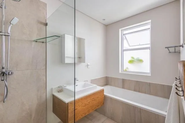 Modern bathroom with wooden vanity, glass shower, and soaking tub