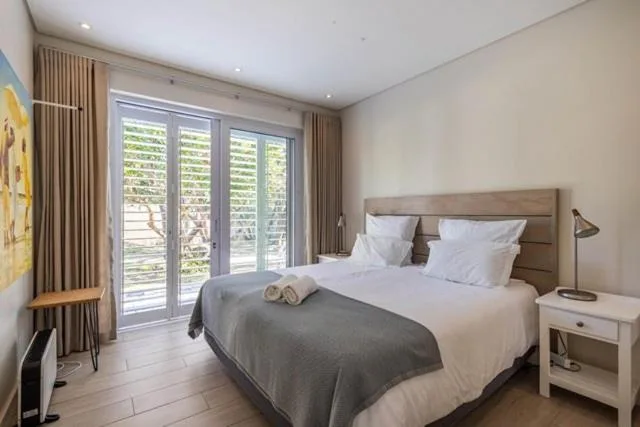 Bright bedroom with queen bed, white linens, and garden view doors